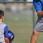 Coaching - Man Kneeling on Baseball Field Beside Man