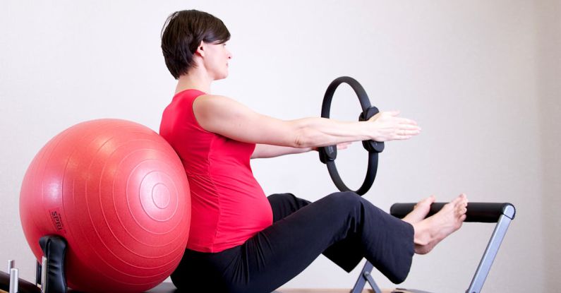 Pilates - Woman in Red Shirt Sitting on Fitness Equipment