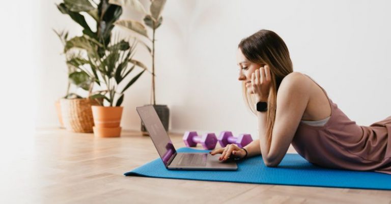 Tracker - Young sportive woman using laptop on floor