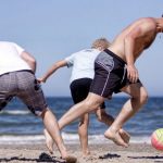 Dynamics - Men and Boy Playing Football on a Sandy Beach