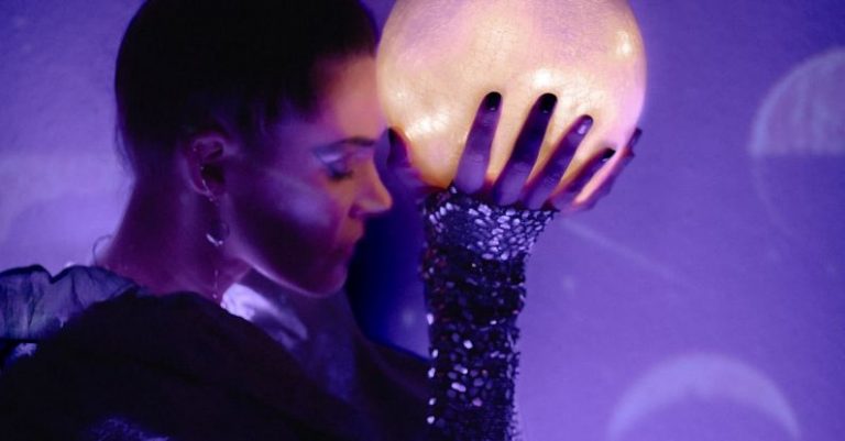 Sleeves - A woman holding a moon ball in front of a purple light